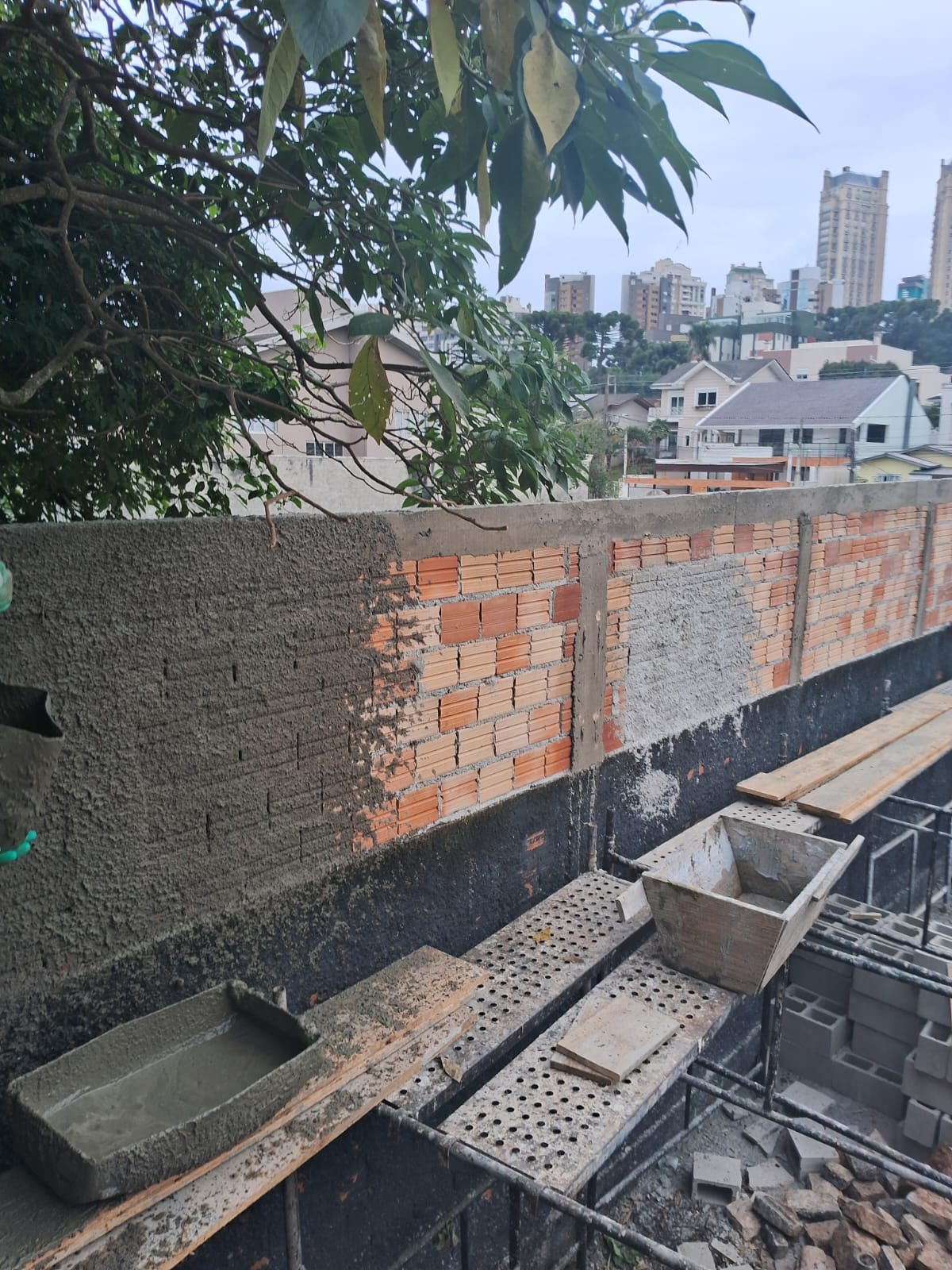 Execução de muro em alvenaria com vista da cidade de Curitiba